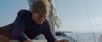 Movie still from “All Is Lost” (2013), directed by J.C. Chandor – An older man leaning on the side of a sail boat; Close Up shot, Low angle