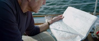 Movie still from “All Is Lost” (2013), directed by J.C. Chandor – An older man sitting on a boat looking at a map; Close Up shot, High angle