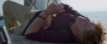Movie still from “All Is Lost” (2013), directed by J.C. Chandor – An older man laying on the ground with his hands on his chest; Close Up shot, Overhead angle