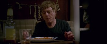 Movie still from “All Is Lost” (2013), directed by J.C. Chandor – A man sitting at a table with a plate of food; Close Up shot, Low angle