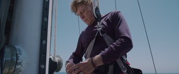 Movie still from “All Is Lost” (2013), directed by J.C. Chandor – A man on a sailboat looking at his cell phone; Medium shot, Low angle