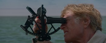 Movie still from “All Is Lost” (2013), directed by J.C. Chandor – A man looking through a pair of binoculars at the ocean; Close Up shot, High angle