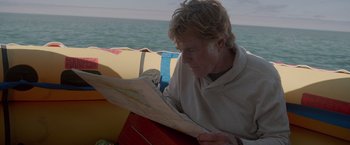 Movie still from “All Is Lost” (2013), directed by J.C. Chandor – A man sitting on a boat looking at a map; Close Up shot, High angle