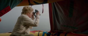 Movie still from “All Is Lost” (2013), directed by J.C. Chandor – A woman taking a picture of the ocean through a window; Medium shot, High angle