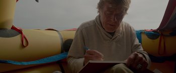 Movie still from “All Is Lost” (2013), directed by J.C. Chandor – An older man writing on a piece of paper; Close Up shot, Low angle