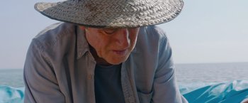Movie still from “All Is Lost” (2013), directed by J.C. Chandor – An older man wearing a straw hat and looking down; Close Up shot, High angle