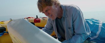 Movie still from “All Is Lost” (2013), directed by J.C. Chandor – A man looking down at a surfboard on the beach; Close Up shot, Low angle