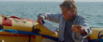 Movie still from “All Is Lost” (2013), directed by J.C. Chandor – A man sitting on a boat in the water; Medium shot, Low angle