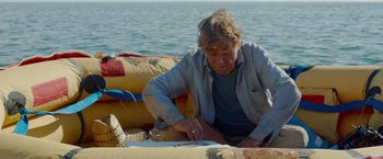 Movie still from “All Is Lost” (2013), directed by J.C. Chandor – An older man sitting on top of a raft near the water; Medium shot, High angle