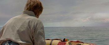 Movie still from “All Is Lost” (2013), directed by J.C. Chandor – A man sitting on a raft in the water; Wide shot, Over the shoulder angle