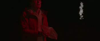 Movie still from “All Is Lost” (2013), directed by J.C. Chandor – An older woman wearing a red jacket holding an object; Medium shot, Low angle