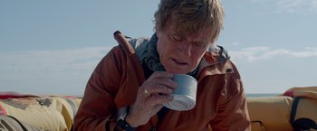 Movie still from “All Is Lost” (2013), directed by J.C. Chandor – An older woman is drinking from a tin can; Close Up shot, Low angle