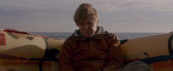 Movie still from “All Is Lost” (2013), directed by J.C. Chandor – A man sitting on a boat in the water; Medium shot, Low angle