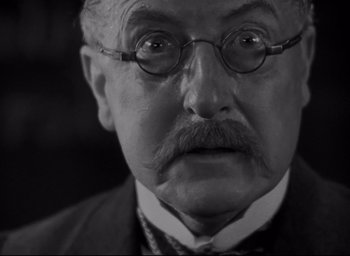 Movie still from “All Quiet on the Western Front” (1930), directed by Lewis Milestone – An older man with a mustache wearing glasses; Close Up shot, Low angle