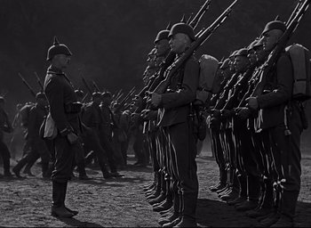 Movie still from “All Quiet on the Western Front” (1930), directed by Lewis Milestone – A black and white photo of a group of men in uniform; Wide shot, Low angle