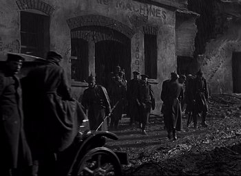 Movie still from “All Quiet on the Western Front” (1930), directed by Lewis Milestone – A black and white photo of men walking down a street; Wide shot, Low angle