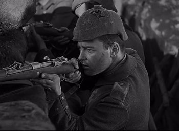 Movie still from “All Quiet on the Western Front” (1930), directed by Lewis Milestone – Black and white photograph of a man holding a rifle; Close Up shot, Low angle