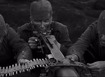 Movie still from “All Quiet on the Western Front” (1930), directed by Lewis Milestone – A man holding a machine gun while sitting on a boat; Medium shot, Low angle