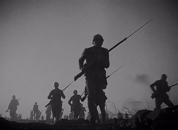 Movie still from “All Quiet on the Western Front” (1930), directed by Lewis Milestone – A black and white photo of a group of soldiers marching; Wide shot, Low angle