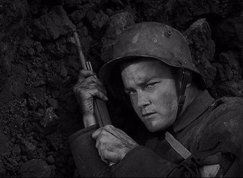 Movie still from “All Quiet on the Western Front” (1930), directed by Lewis Milestone – A man holding a rifle in a cave; Close Up shot, High angle