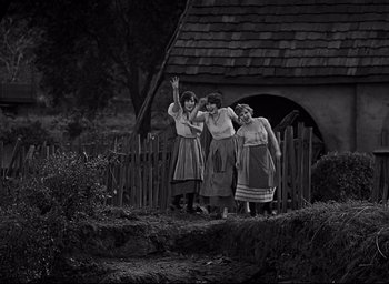 Movie still from “All Quiet on the Western Front” (1930), directed by Lewis Milestone – A group of women standing next to each other near a fence; Wide shot, High angle