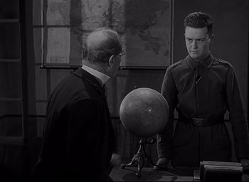 Movie still from “All Quiet on the Western Front” (1930), directed by Lewis Milestone – Two men are standing in front of a globe in a room; Medium shot, Over the shoulder angle