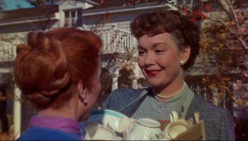 Movie still from “All That Heaven Allows” (1955), directed by Douglas Sirk – Two women talking to each other in front of a building; Close Up shot, Over the shoulder angle