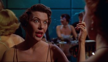 Movie still from “All That Heaven Allows” (1955), directed by Douglas Sirk – A woman is smoking a cigarette in front of other people; Close Up shot, Low angle
