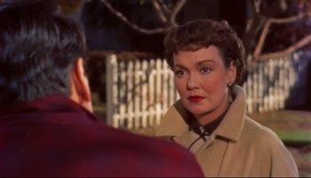 Movie still from “All That Heaven Allows” (1955), directed by Douglas Sirk – A woman wearing a trench coat talking to a man in a red shirt; Close Up shot, Over the shoulder angle