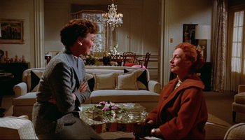 Movie still from “All That Heaven Allows” (1955), directed by Douglas Sirk – Two women in a living room talking to each other; Medium shot, High angle