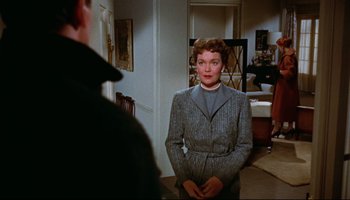 Movie still from “All That Heaven Allows” (1955), directed by Douglas Sirk – A woman wearing a suit standing next to a man; Medium shot, Over the shoulder angle