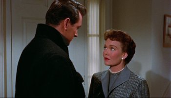 Movie still from “All That Heaven Allows” (1955), directed by Douglas Sirk – A man and a woman standing next to each other in front of a window; Medium shot, Over the shoulder angle