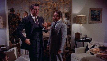 Movie still from “All That Heaven Allows” (1955), directed by Douglas Sirk – Two men in suits and ties standing next to each other in a living room; Medium shot, Low angle