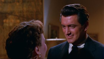 Movie still from “All That Heaven Allows” (1955), directed by Douglas Sirk – A man in a suit and tie talking to a woman in a black suit; Close Up shot, Over the shoulder angle