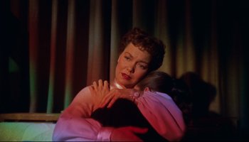 Movie still from “All That Heaven Allows” (1955), directed by Douglas Sirk – An older woman hugging a younger woman in front of a curtain; Medium shot, High angle