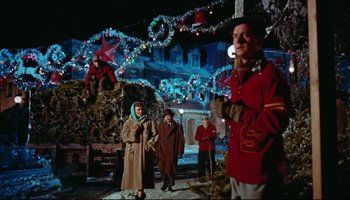 Movie still from “All That Heaven Allows” (1955), directed by Douglas Sirk – A group of people standing in front of christmas lights; Wide shot, Low angle