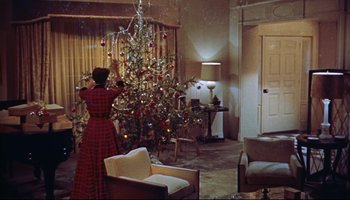 Movie still from “All That Heaven Allows” (1955), directed by Douglas Sirk – A woman standing in front of a decorated christmas tree; Extreme Wide shot, High angle