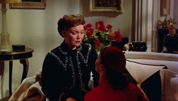 Movie still from “All That Heaven Allows” (1955), directed by Douglas Sirk – Two women are talking in a living room with roses; Medium shot, Over the shoulder angle