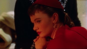 Movie still from “All That Heaven Allows” (1955), directed by Douglas Sirk – A woman in a red dress and a red hat is holding her hand to her face; Close Up shot, High angle