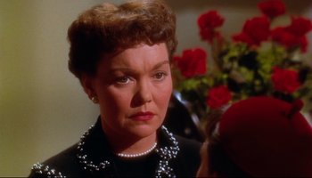 Movie still from “All That Heaven Allows” (1955), directed by Douglas Sirk – An older woman wearing a black dress and a pearl necklace; Close Up shot, Over the shoulder angle