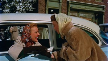 Movie still from “All That Heaven Allows” (1955), directed by Douglas Sirk – Two women in fur coats are sitting in the back of a car; Medium shot, High angle