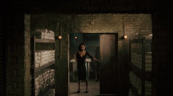 Movie still from “Snowfall” (2017), directed by Hiro Murai – A woman standing in front of shelves in a room; Wide shot, Low angle