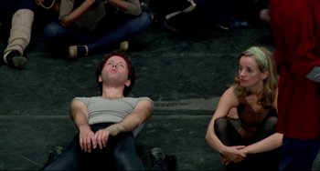 Movie still from “All That Jazz” (1979), directed by Bob Fosse – A man and a woman sitting on the ground; Medium shot, High angle
