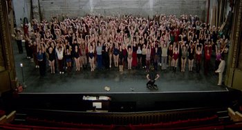 Movie still from “All That Jazz” (1979), directed by Bob Fosse – A group of people standing on a stage in front of an audience; Extreme Wide shot, Overhead angle