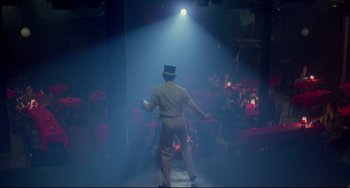 Movie still from “All That Jazz” (1979), directed by Bob Fosse – A man in a top hat and a suit is in a dark room; Wide shot, High angle