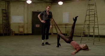 Movie still from “All That Jazz” (1979), directed by Bob Fosse – A man in black tights is on the ground while another man in black tights is on the floor; Wide shot, Low angle