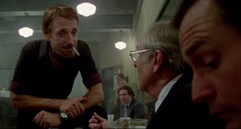 Movie still from “All That Jazz” (1979), directed by Bob Fosse – A man sitting at a table talking to another man in a suit; Medium shot, Over the shoulder angle