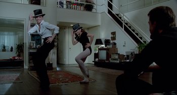 Movie still from “All That Jazz” (1979), directed by Bob Fosse – A woman in a top hat dancing in a living room; Wide shot, High angle