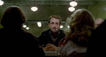 Movie still from “All That Jazz” (1979), directed by Bob Fosse – A man sitting in front of two other people at a table; Close Up shot, Over the shoulder angle