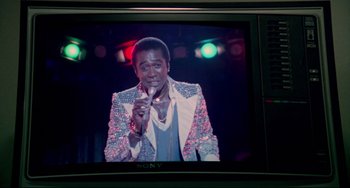 Movie still from “All That Jazz” (1979), directed by Bob Fosse – A person holding a microphone on a tv screen; Close Up shot, Low angle